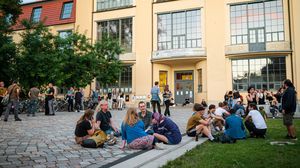 Studierende sitzen vor dem Hauptgebäude