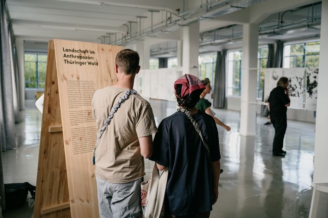 Projekt: »Landschaft im Anthropozän – Thüringer Wald«, Foto: Stiftung Baukultur Thüringen, Henry Sowinski Ausstellungsbesuchende lesen aufmerksam die Projektbeschreibung»Landschaft im Anthropozän – Thüringer Wald«