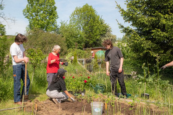 Projekt »Forestmade«, Foto: Julian Linden mehrere Personen aus der Entfernung fotografiert, die über etwas im Garten beraten
