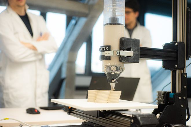 Projekt »Print4PR«, Foto: Julian Linden zwei Personen sehen dem 3D-Drucker bei der Arbeit zu