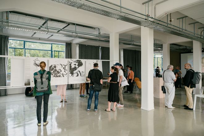 Projekt: »Landschaft im Anthropozän – Thüringer Wald«, Foto: Stiftung Baukultur Thüringen, Henry Sowinski Besuchende in der Ausstellung vor großformatigen Plänen