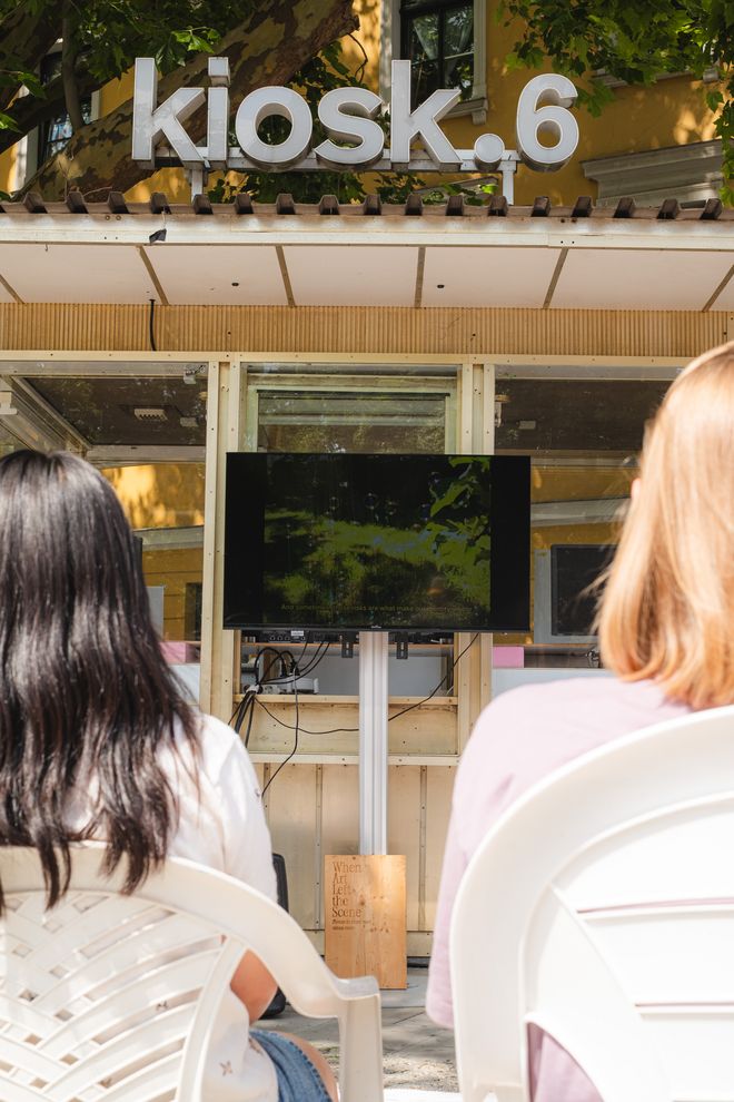 Projekt »Biennal of Care«, Foto: Julian Linden zwei Personen schauen auf einen Monitor, der vor dem kiosk.6 in Weimar aufgebaut ist