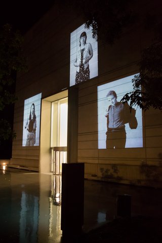 The photo shows 3 black-and-white portraits from Larissa Barth's photo series walter ≠ bauhaus, which are projected onto the on the façade of the Bauhaus Museum Weimar at night.
