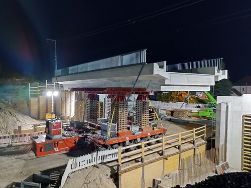 Foto in der Nacht von einer im Bau befindlichen Brücke mit Baueinrichtung.