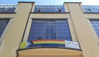 The photo shows a banner with the »Intersex-Inclusive Progress Pride Flag« hanging from the balcony of the Main Building of the Bauhaus-Universität Weimar.