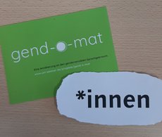 Das Symbolbild zeigt eine grüne Werbepostkarte zum »Gender-O-Mat« des Gleichstellungsbüros sowie ein Blatt Papier mit der Aufschrift »*innen«.