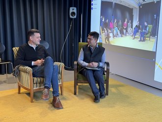 Universitätspräsident Prof. Peter Benz beglückwünscht den Preisträger während der Urkundenverleihung im Hybriden Lernatelier. Foto: Marit Haferkamp, Newsteam