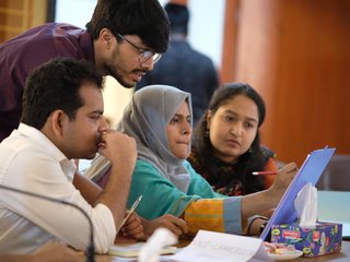 vier Projektpartner aus Bangladesch schauen konzentriert auf gemeinsame Notizen