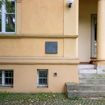 Ansicht einer Eingangssituation eines Hauses. Links der durch eine Stütze gegliederten Eingangssituation befindet sich eine Bronzetafel mit der Inschrift: Ghettohaus 1940 – 1942 1900 Wohnhaus des Ehepaares Friedrich Fleischer, Kunstschulprofessor Jenny-Fleischer-Alt, Kammersängerin 1940/41 Zwangseinweisung jüdischer Bürger Zum Gedenken an: Jenny Fleischer-Alt Freitod 1942 Edith Gál Freitod 1942 Ilka Gál Tod 1942 Käthe Friedländer Deportation 1942 verschollen Martha Kreiss Tod 1944 Eduard Rosé, Deportation 1942 Cellist, Konzertmeister Tod 1943 in Theresienstadt