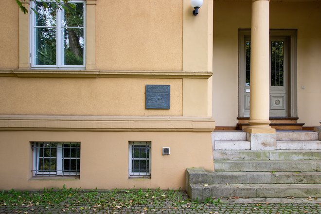 Ansicht einer Eingangssituation eines Hauses. Links der durch eine Stütze gegliederten Eingangssituation befindet sich eine Bronzetafel mit der Inschrift: Ghettohaus 1940 – 1942 1900 Wohnhaus des Ehepaares Friedrich Fleischer, Kunstschulprofessor Jenny-Fleischer-Alt, Kammersängerin 1940/41 Zwangseinweisung jüdischer Bürger Zum Gedenken an: Jenny Fleischer-Alt Freitod 1942 Edith Gál Freitod 1942 Ilka Gál Tod 1942 Käthe Friedländer Deportation 1942 verschollen Martha Kreiss Tod 1944 Eduard Rosé, Deportation 1942 Cellist, Konzertmeister Tod 1943 in Theresienstadt