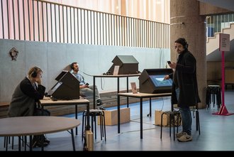 Ansicht einer Ausstellung mit verschiedenen Bildschirmen, an denen Menschen die Transcultural Listening Map ausprobieren